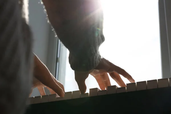 Junge Frau spielt Klavier in der Nähe von Fenster zu Hause, Nahaufnahme — Stockfoto