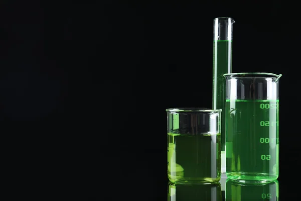 Verrerie de laboratoire avec des liquides colorés sur fond noir. Espace pour le texte — Photo