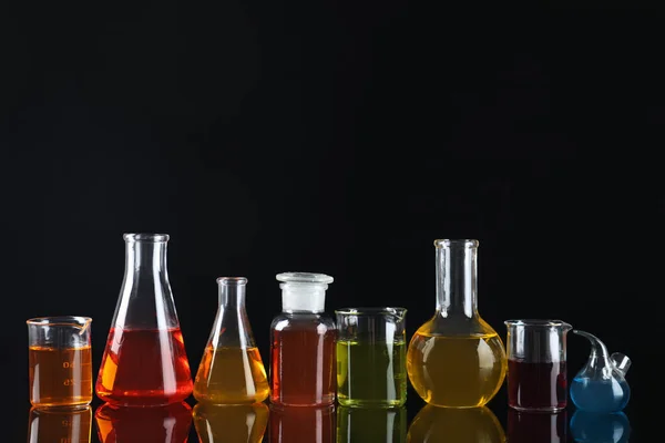 Laboratory glassware with colorful liquids on black background — Stock Photo, Image