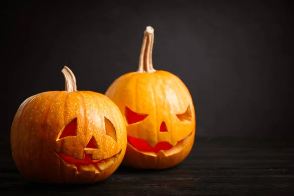 Spookachtige Jack pompoen koplampjes op houten tafel tegen een zwarte achtergrond. Halloween decoratie — Stockfoto