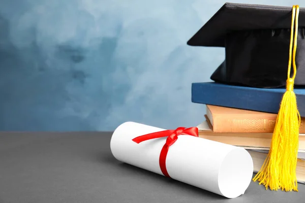 Καπέλο αποφοίτησης, βιβλία και δίπλωμα φοιτητή σε γκρι τραπέζι με ανοιχτό μπλε φόντο. Χώρος για κείμενο — Φωτογραφία Αρχείου
