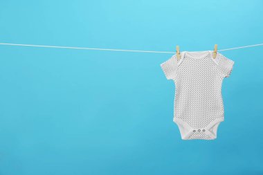 Bebek onesie mavi arka plan, metin için alan karşı giysi hattı asılı. Çamaşır günü