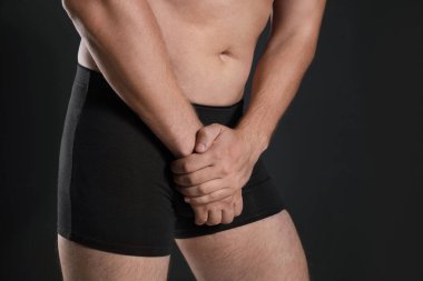 Siyah arka planda acı çeken adam, yakın çekim. Üroloji sorunları