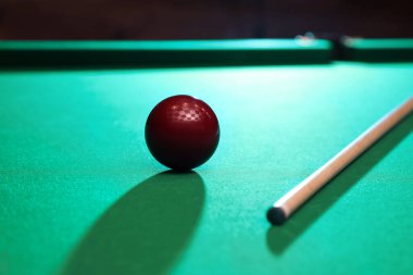 Kırmızı bilardo topu ve ıstaka masada.
