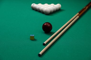 Bilardo topları, tebeşir ve ıstakalar masada.