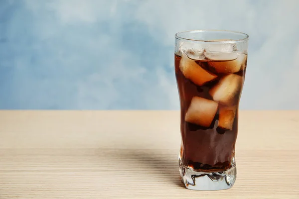 Gelas minuman soda menyegarkan di meja kayu dengan latar belakang biru, ruang untuk teks — Stok Foto