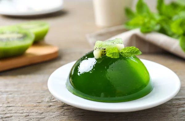 Delicious fresh green jelly with kiwi slices and mint on wooden table