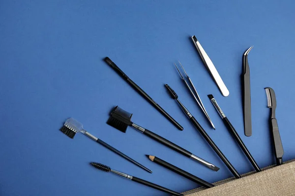 Conjunto de ferramentas de sobrancelha profissional no fundo azul, flat lay — Fotografia de Stock