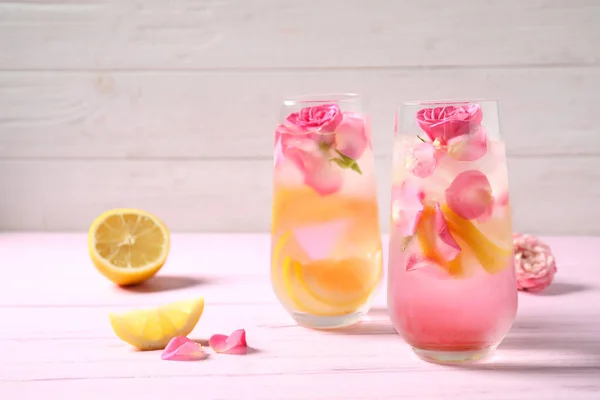 Delicious refreshing drink with lemon and roses on pink wooden table — Stock Photo, Image