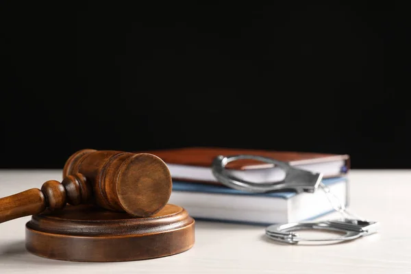 Martillo del juez, esposas y libros sobre mesa blanca sobre fondo negro. Concepto de Derecho penal — Foto de Stock