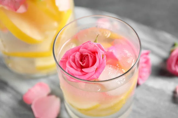 Deliciosa bebida refrescante con limón y rosa en la mesa gris, primer plano —  Fotos de Stock