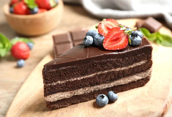 Delicioso bolo de chocolate fresco com bagas na mesa de madeira, close-up — Fotografia de Stock