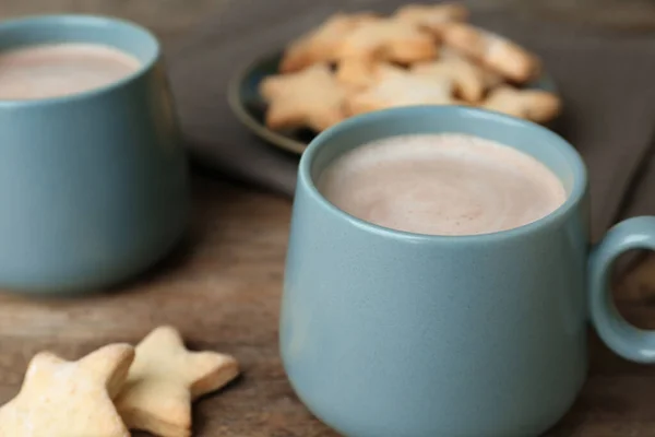 Композиція зі смачним гарячим напоєм з какао та печивом на дерев'яному столі, крупним планом — стокове фото