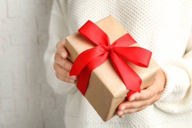 Genç bir kadın Noel hediyesini arka planda tutuyor, yakın plan.
