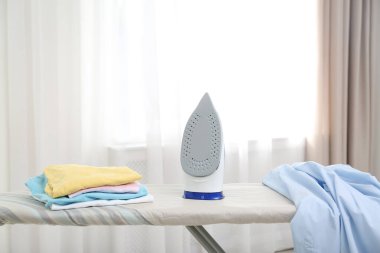 İçinde modern demir ve temiz giysiler olan bir tahta. Çamaşır günü