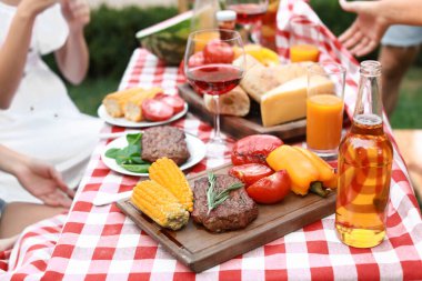 Barbekü partisindeki arkadaşlar, açık havada pişirilmiş et ve sebzelerle masaya odaklanın.