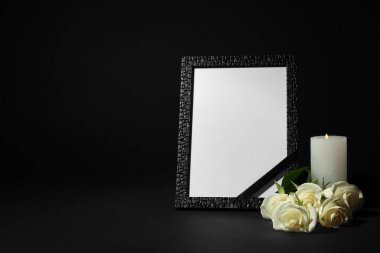 Siyah arka plan karşı koyu masa üzerinde kurdele, beyaz gül ve mum ile Cenaze fotoğraf çerçevesi. Tasarım alanı