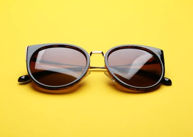 Sarı arka planda şık güneş gözlükleri. Modaya uygun aksesuarlar.