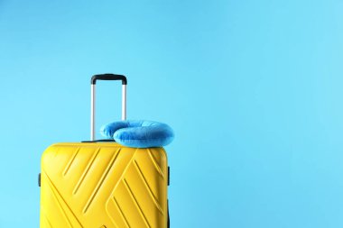 Sarı bavul ve açık mavi arkaplanda seyahat yastığı, metin için boşluk