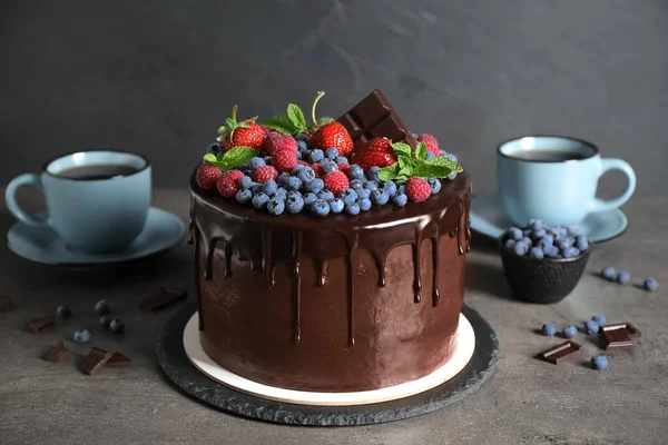 방금 만들어 진 맛좋은 초콜릿 케이크에 딸기로 장식된 회색 테이블 — 스톡 사진