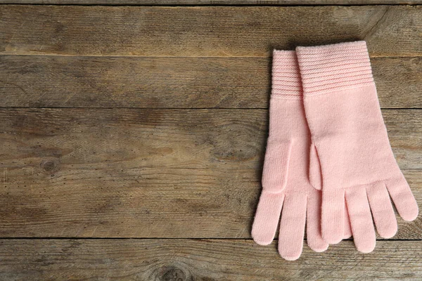 Stylish pink gloves on wooden background, top view with space for text. Autumn clothes