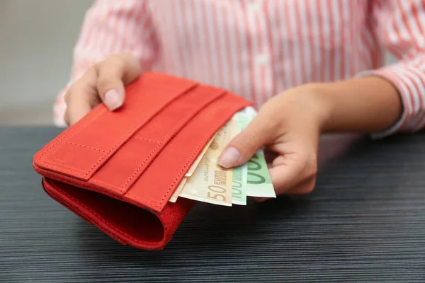 Женщина кладет банкноты евро в бумажник, крупным планом — стоковое фото