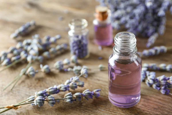 Botella de aceite esencial natural y flores de lavanda sobre fondo de madera —  Fotos de Stock