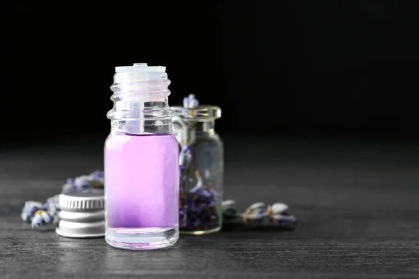 Garrafas de óleo essencial natural e flores de lavanda em mesa de madeira escura. Espaço para texto — Fotografia de Stock