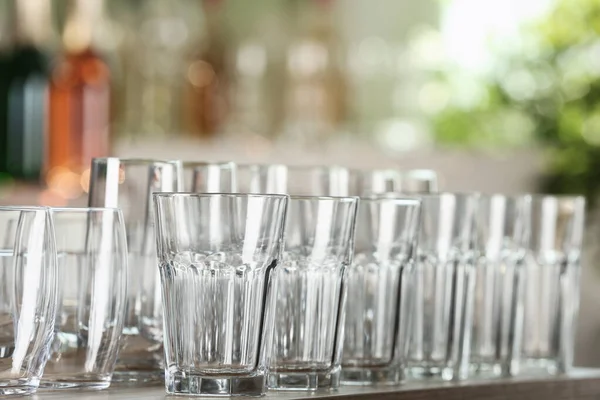 Lege glazen op houten tafel tegen wazige achtergrond — Stockfoto