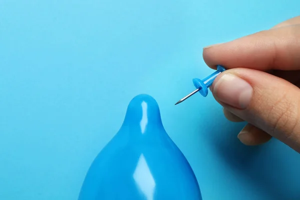 Donna piercing preservativo gonfiato con perno su sfondo azzurro, primo piano. Sesso sicuro — Foto Stock