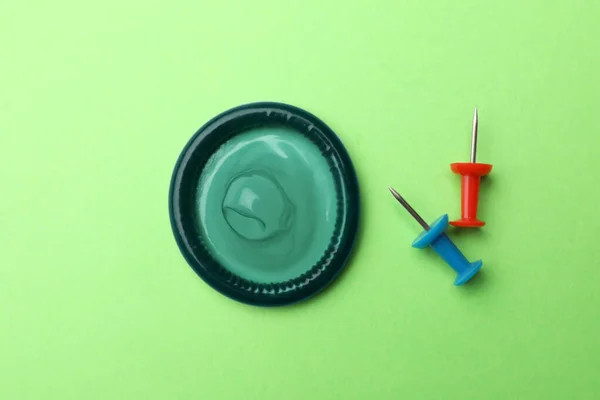 Blauw condoom en pin op groene ondergrond, plat gelegd — Stockfoto