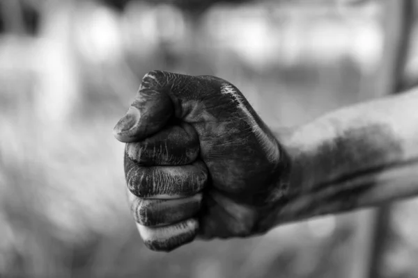 Trabalhador sujo cerrando punho no fundo borrado, close-up de mão. Efeito preto e branco — Fotografia de Stock
