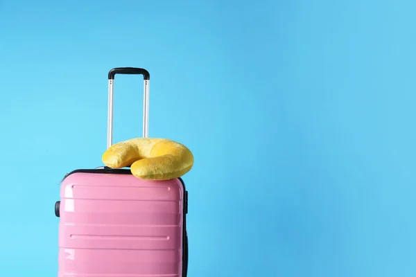 Valigia rosa e cuscino da viaggio su sfondo azzurro, spazio per il testo — Foto Stock