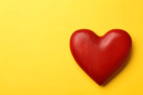Czerwone drewniane serce na żółtym tle, widok z góry. Miejsce na tekst — Zdjęcie stockowe
