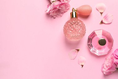 Açık pembe arka planda parfüm şişeleri ve çiçeklerle düz kompozisyon, metin için boşluk