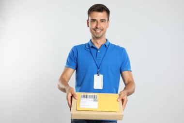Beyaz arka planda paketi ve zarfı olan mutlu genç kurye