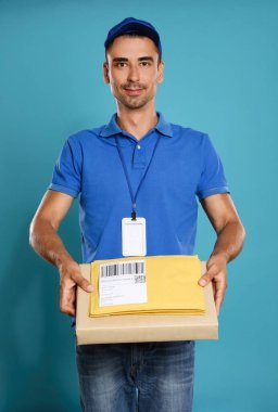 Mavi arka planda paketleri ve zarfları olan mutlu genç kurye.