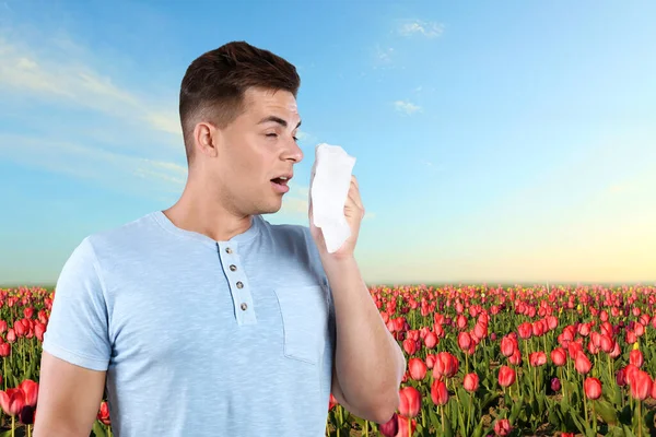 Junger Mann mit Allergie und blühendem Feld im Hintergrund — Stockfoto
