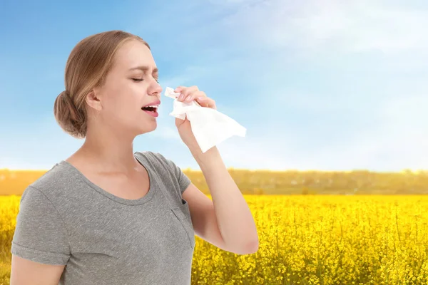 Young woman suffering from allergy and blooming field on background — Stock Photo, Image