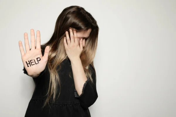 Junge Frau mit Hilfe von Wörtern, die auf ihre Handfläche vor hellem Hintergrund geschrieben sind, konzentriert sich auf die Hand. Raum für Text — Stockfoto