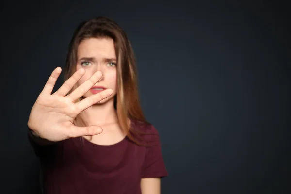 Junge Frau macht Stop-Geste vor dunklem Hintergrund, konzentriert sich auf die Hand. Raum für Text — Stockfoto