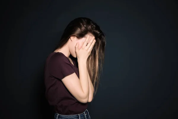 Zaklatott fiatal nő sír a sötét háttérben. A szöveg helye — Stock Fotó