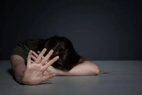 Νεαρή γυναίκα κάνει στάση χειρονομία, ενώ βρίσκεται στο πάτωμα σε εσωτερικούς χώρους. Χώρος για κείμενο — Φωτογραφία Αρχείου