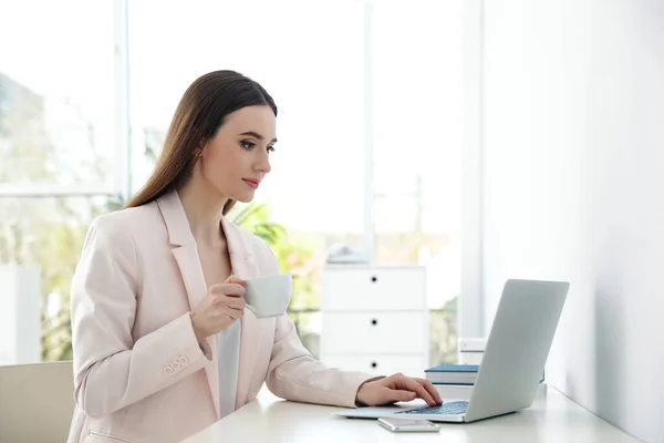 Pengusaha wanita muda menggunakan laptop di meja di kantor — Stok Foto