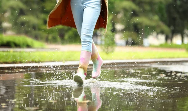 Frau mit Gummistiefeln, die in Pfützen laufen, Großaufnahme. Regenwetter — Stockfoto