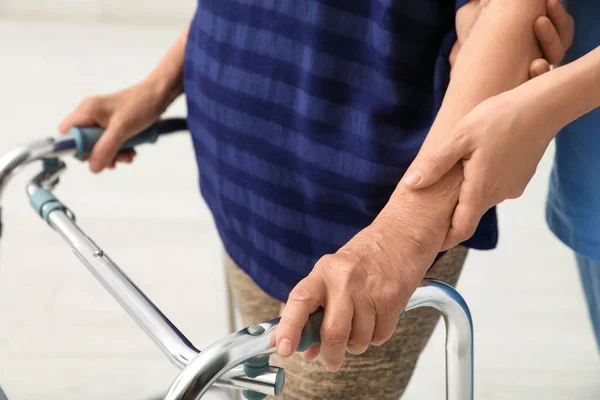 Gondozó segít idős nő gyalogos keret a könnyű háttér, közelkép — Stock Fotó