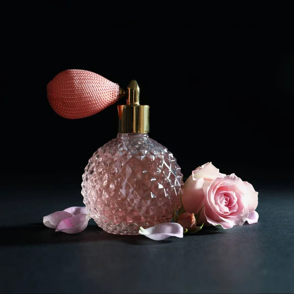 Botella vintage de perfume y hermosa flor sobre fondo negro — Foto de Stock