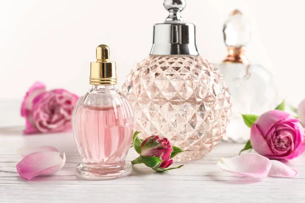 Different bottles of perfume and flowers on light background, closeup — Stock Photo, Image