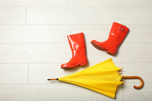 Ombrello a colori e stivali di gomma sul pavimento in legno, posa piatta. Spazio per testo — Foto Stock
