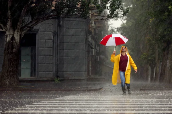 雨の日に屋外でカラフルな傘を持つ幸せな若い男 — ストック写真